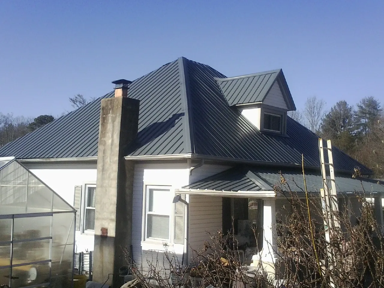 Dark blue standing seam metal roof on a white farmhouse with dormer — Slate & Tile Roof Repair by Roofing Brothers in Naperville