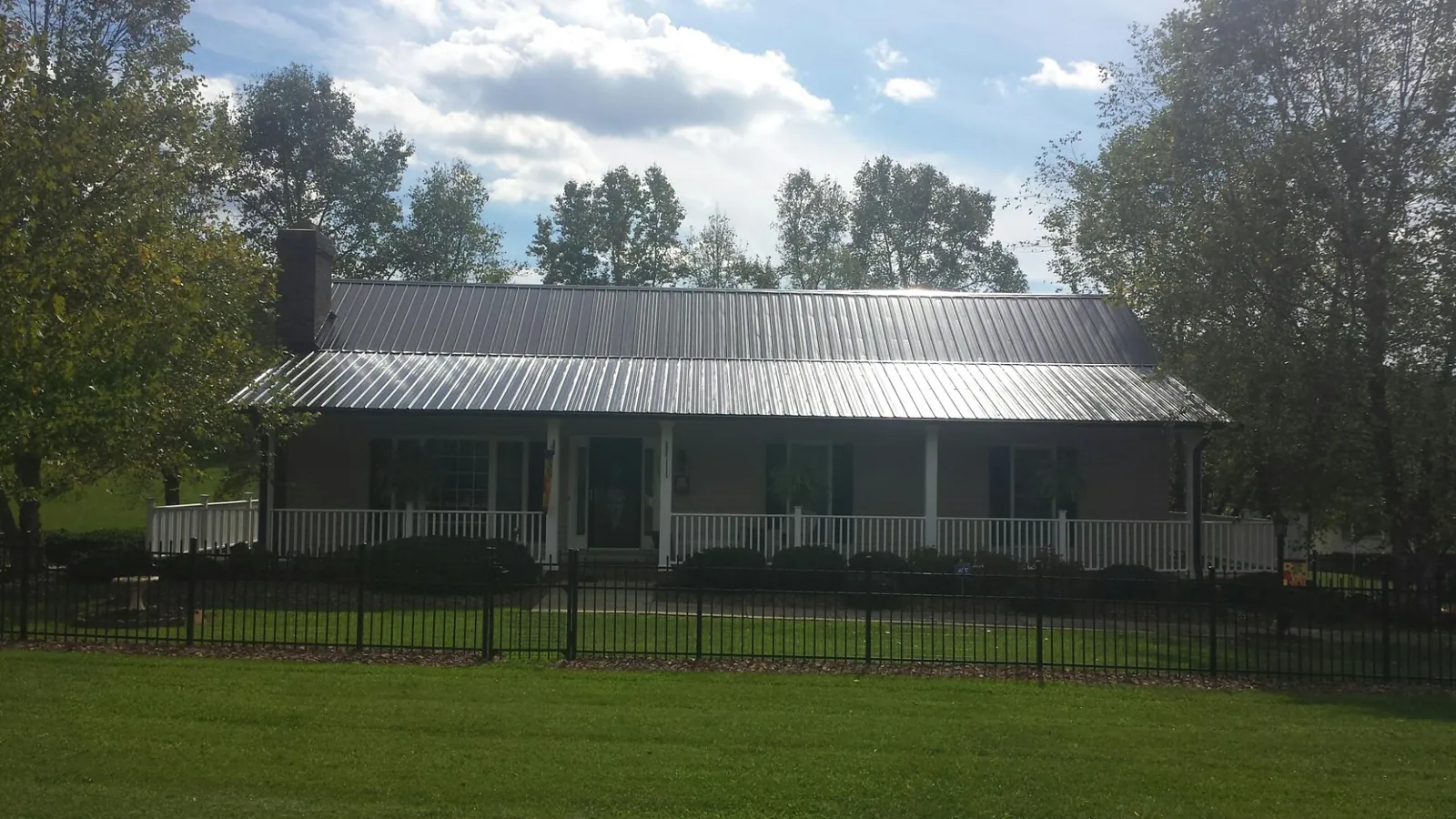 Gray metal roof on a brick ranch with a full width front porch — Gutter Guard Installation work by our crew in Naperville