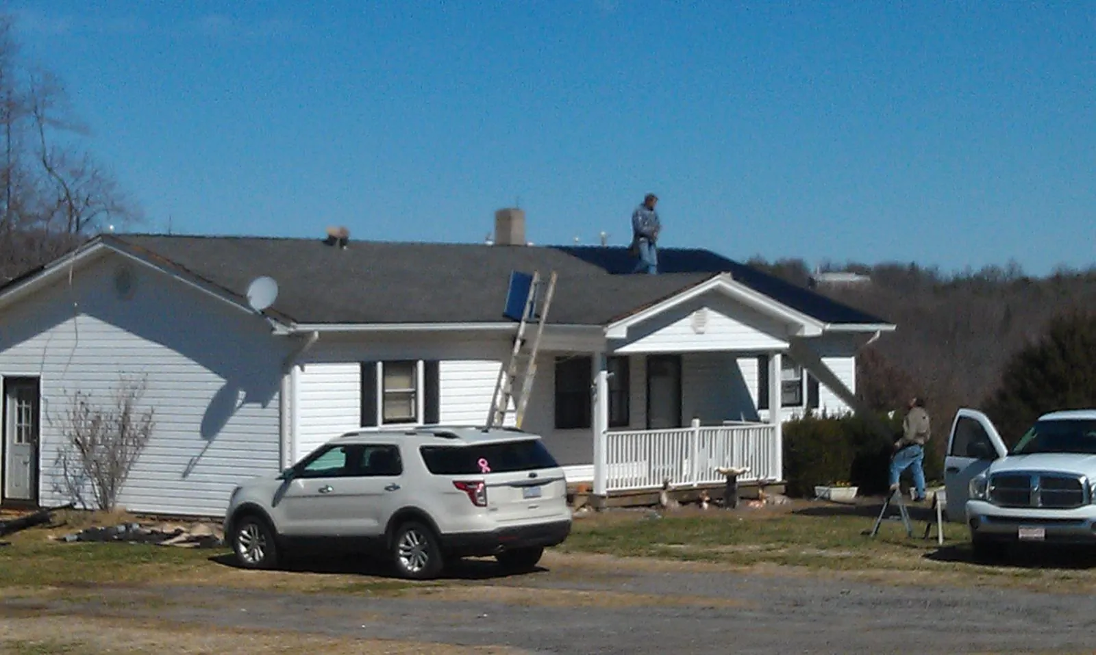 Roofers stripping shingles from a white ranch house roof in Naperville
