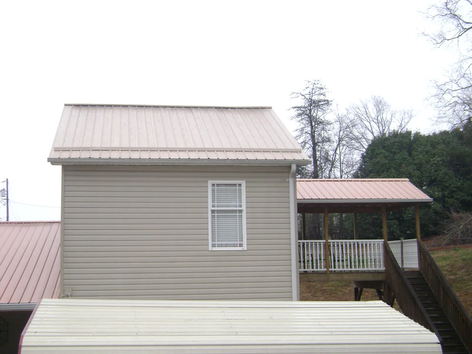 Tan metal roofs on a two story addition and attached porch, from a Roof Replacement job in Naperville