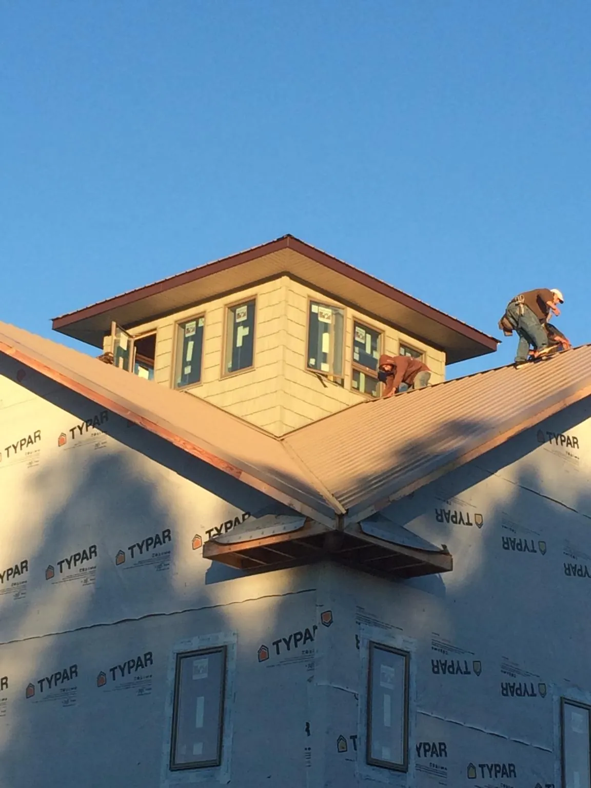 Roofers working around a rooftop cupola on a new metal roof at sunset — Roof Waterproofing in Naperville by Roofing Brothers